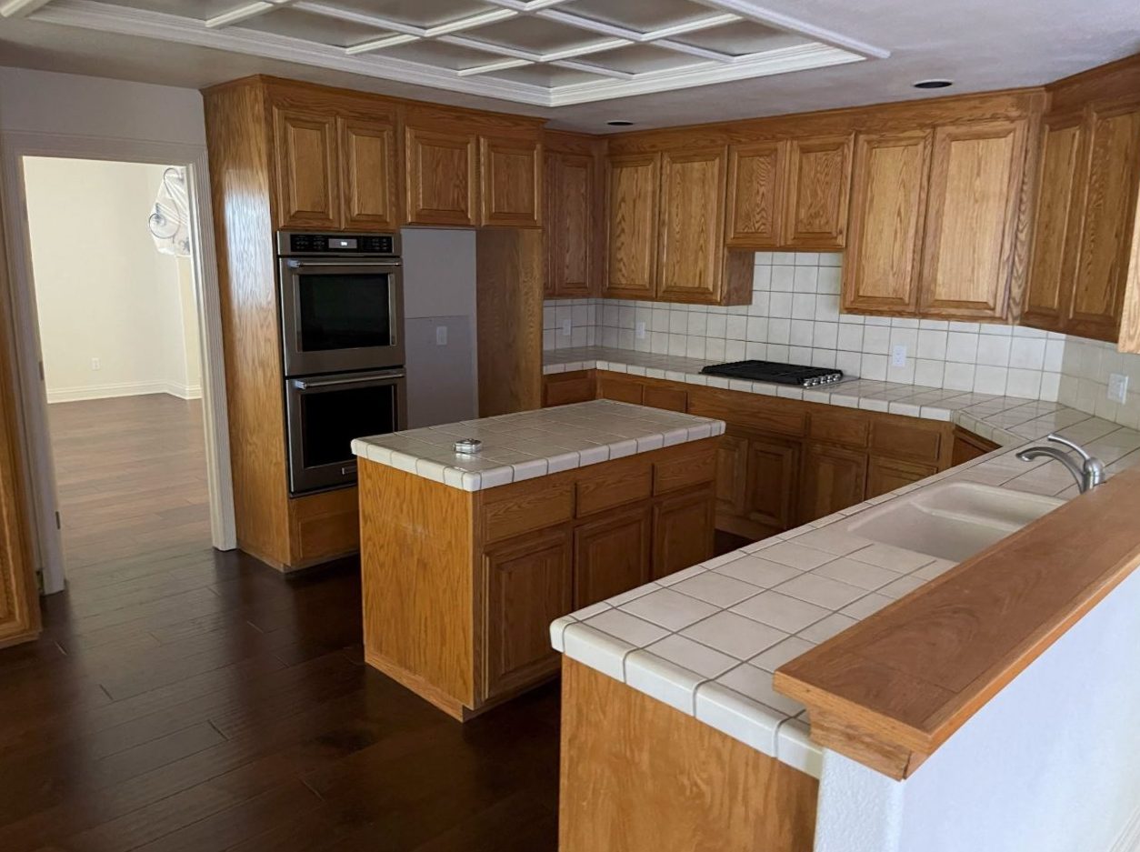 Kitchen before remodeling with oak cabinets and tile counters